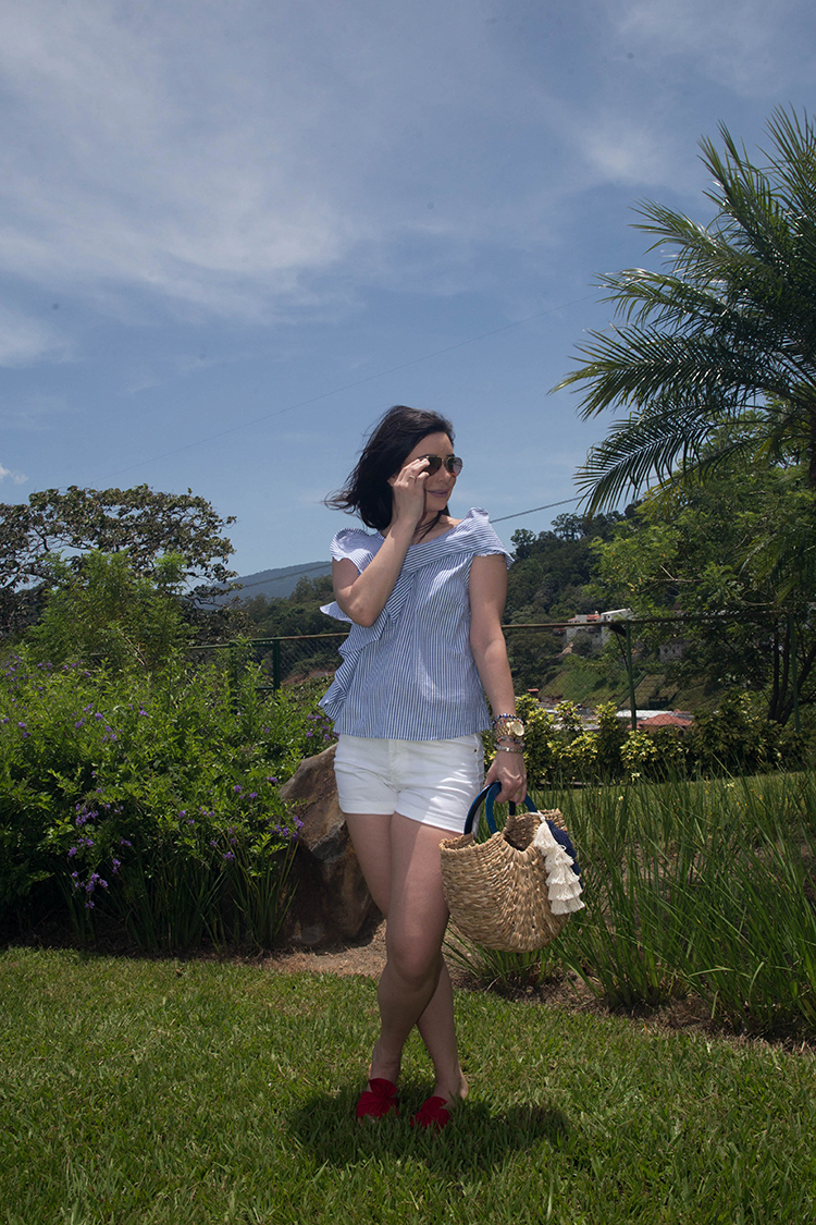 Blusa de volantes, sandalias rojas y cartera de mimbre